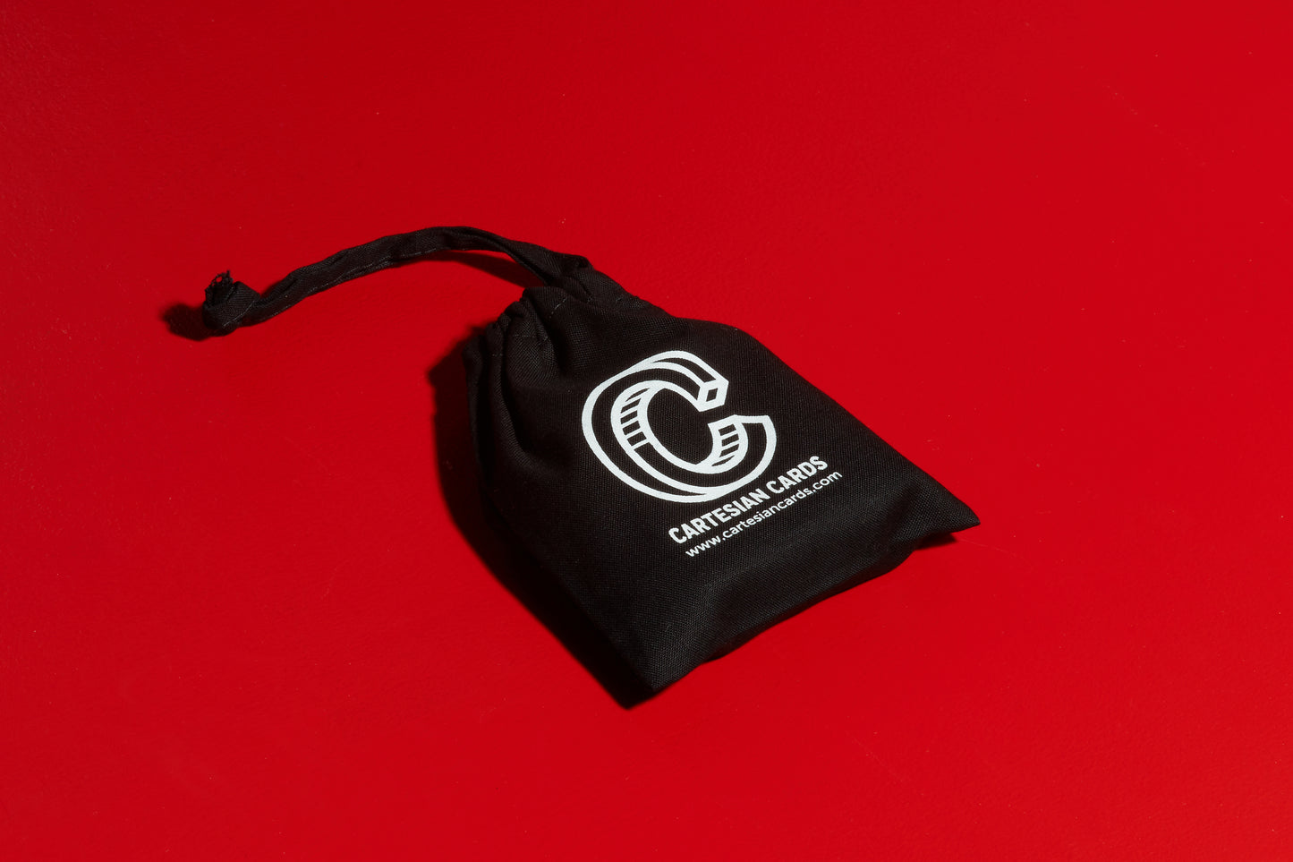 Black playing card travel pouch with deck inside on a red surface