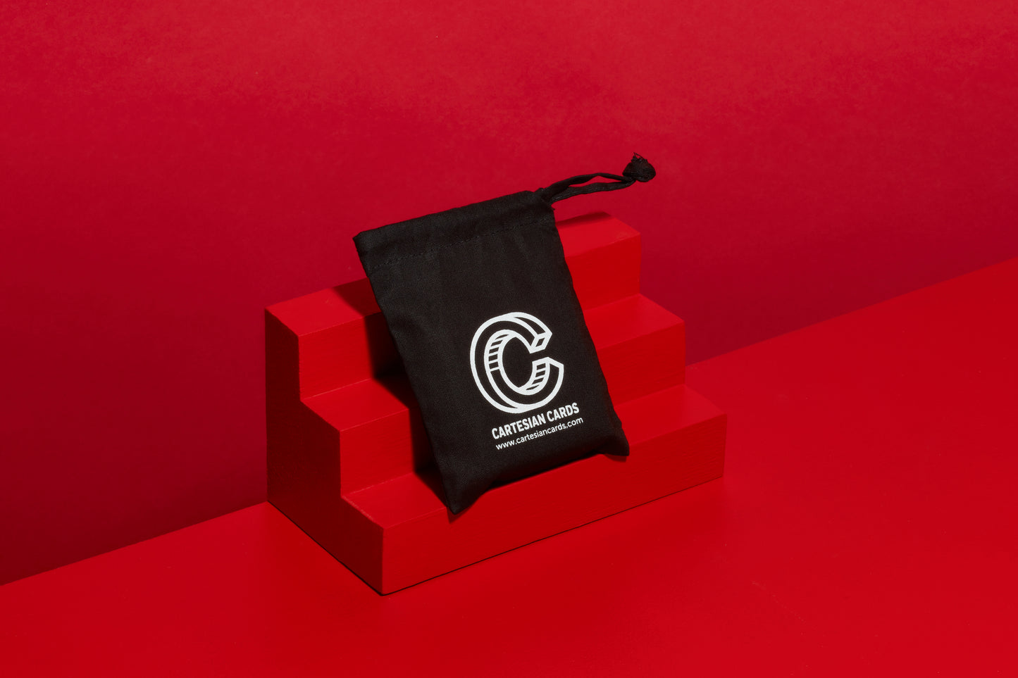 Black playing card travel pouch on a red geometric steps