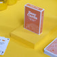 Beer-themed playing cards on a yellow surface with a glass of beer and beer bottles.