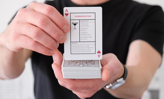 Hand holding up the Cosmopolitan Cocktail Card (Ace of hearts)