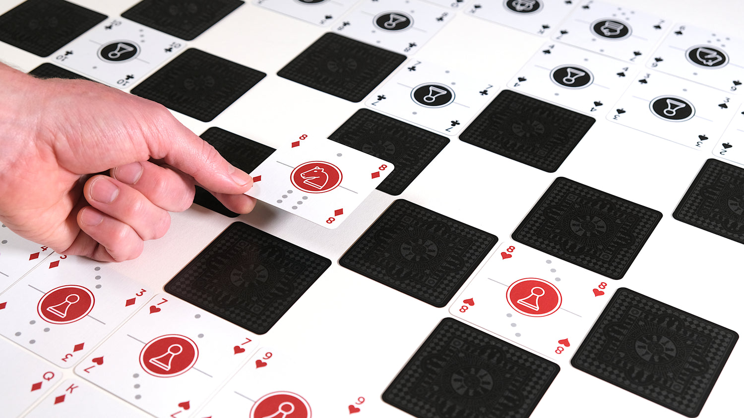 One Deck Game Cards laid out as chess board with hand playing a knight (cover image for Kickstarter video)