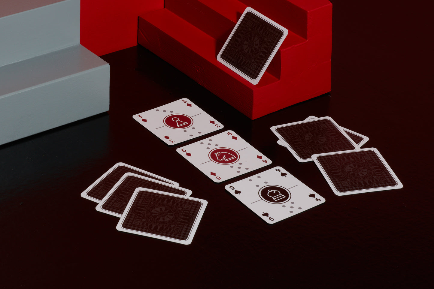 A deck of One Deck Game Cards playing cards laid out to play dominoes with red and grey geometric objects